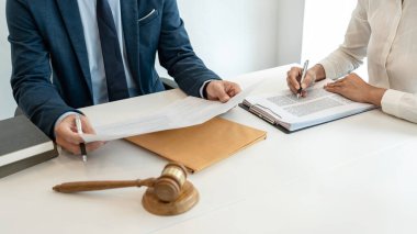 Erkek avukat, hukuk firmasında sözleşme imzalamadan önce iş kadınına danışma şartlarını ve şartları açıklayan yasal bir belgeye işaret ediyor..