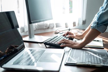 Asyalı kadın programcı, yazılım geliştirme ofisinde çoklu ekran laptopuyla çalışırken yeni web sitesi veya uygulamalar için dizüstü bilgisayarla kod verileri yazıyor