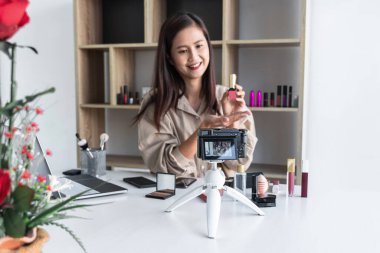 Mutlu gülümseyen zarif kadın ya da video kaydında fırçasıyla güzellik blogcusu. İnceleme ürünü kamera ekranında video blogları hakkında özel ders hazırlıyor..