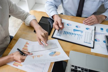 İki işletme yöneticisi yeni proje başarı istatistikleri ile tartışıyorlar, Ortaklar her iki şirket için profesyonel yatırımcılarla görüşüyor belge ile birlikte proje başlatıyorlar.