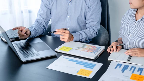 Dwóch Współpracowników Biznesowych Wskazujących Dane Biznesowe Laptopie Robiących Notatki Temat — Zdjęcie stockowe