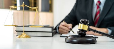 Sözleşme kağıtları, kitap ve ahşap tokmakla çalışan bir erkek avukat veya noter mahkeme salonunda, hukuk ve hukuk hizmetleri kavramında masaya oturur..