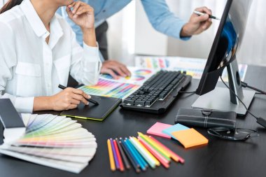 Yaratıcı grafik tasarımcı takımı, iş yerinde yeni bir koleksiyon oluşturmak için renk örnekleri çizelgesi üzerinde çalışıyor.