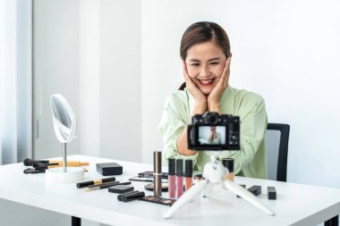 Kadın blogcu, makyaj malzemesi kozmetik inceleme ürünü ve canlı yayın videosunu ofis stüdyosundaki kamera ekranında öğretmenliğe sunuyor..