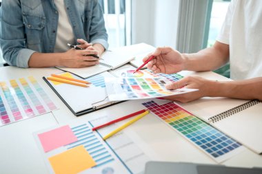 Yaratıcı grafik tasarımcı takımı, iş yerinde yeni bir koleksiyon oluşturmak için renk örnekleri çizelgesi üzerinde çalışıyor..