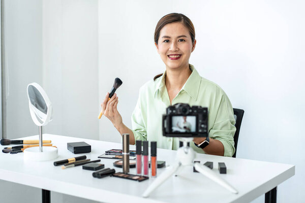 Женщина-блоггер показывает настоящее время макияж учебник красоты косметического обзора продукта и трансляции в прямом эфире потокового видео в социальной сети обучения онлайн на экране камеры.