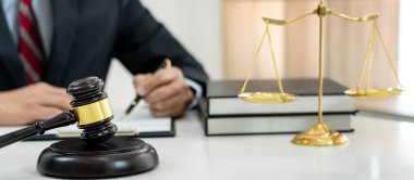 Sözleşme kağıtları, kitap ve ahşap tokmakla çalışan bir erkek avukat veya noter mahkeme salonunda, hukuk ve hukuk hizmetleri kavramında masaya oturur..