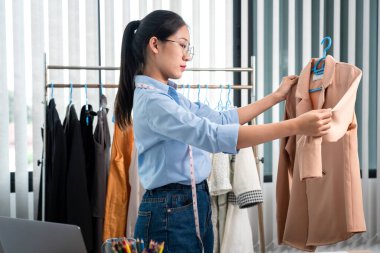 Çalışan ve düşünen kadın moda tasarımcısı atölyede yeni kıyafet koleksiyonu ürünü yapmak için renk örnekleri ve kumaş seçmeye karar verdi.