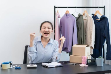 Moda tasarımcısı kadın ürünleri satar ve müşteriden sipariş alır ve müşteriye eve teslimat için kıyafet paketlerini kutulara doldurur..