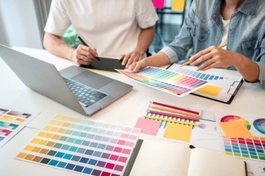Yaratıcı grafik tasarımcı takımı, iş yerinde yeni bir koleksiyon oluşturmak için renk örnekleri çizelgesi üzerinde çalışıyor..
