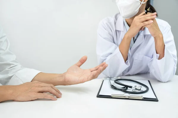 一位戴医疗面罩的女医生在讨论疾病诊断时 正在倾听病人的症状 并在临床上为病人提供身体检查后的治疗方法 — 图库照片