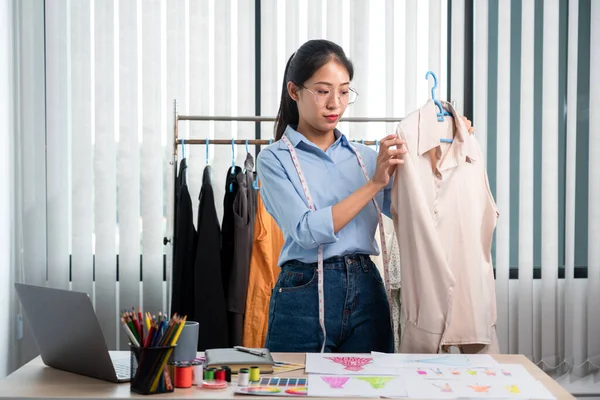 Women fashion designer stylist working and thinking decide choosing color samples and fabric to making new clothes collection product in the workshop.