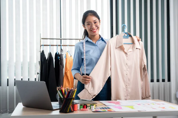 Çalışan ve düşünen kadın moda tasarımcısı atölyede yeni kıyafet koleksiyonu ürünü yapmak için renk örnekleri ve kumaş seçmeye karar verdi.