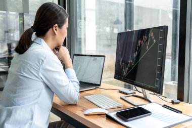 İş kadını yatırımcı yeni bir proje planlıyor ve ekran ile grafik verilerini analiz ediyor. Veriler sunuluyor ve bir borsa üzerinde anlaşma yapılıyor..
