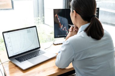 İş kadını yatırımcı yeni bir proje planlıyor ve ekran ile grafik verilerini analiz ediyor. Veriler sunuluyor ve bir borsa üzerinde anlaşma yapılıyor..