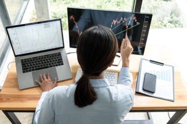 İş kadını yatırımcı yeni bir proje planlıyor ve ekran ile grafik verilerini analiz ediyor. Veriler sunuluyor ve bir borsa üzerinde anlaşma yapılıyor..