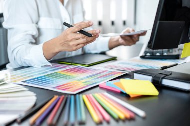 İş yerindeki grafik tabletinde renk seçimi ve çizim üzerine çalışan genç yaratıcı grafik tasarımcısı, yeni bir koleksiyon oluşturmak için ilhamda seçim renklendirmesi için renk örnekleri çizelgesi