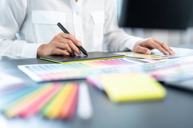 İş yerindeki grafik tabletinde renk seçimi ve çizim üzerine çalışan genç yaratıcı grafik tasarımcısı, yeni bir koleksiyon oluşturmak için ilhamda seçim renklendirmesi için renk örnekleri çizelgesi