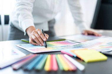 İş yerindeki grafik tabletinde renk seçimi ve çizim üzerine çalışan genç yaratıcı grafik tasarımcısı, yeni bir koleksiyon oluşturmak için ilhamda seçim renklendirmesi için renk örnekleri çizelgesi