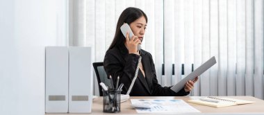 İş kadını, yeni iş yatırımları hakkında konuşmak ve ofiste çalışırken dokümandaki bilgileri kontrol etmek için müvekkiline çağrı alıyor.