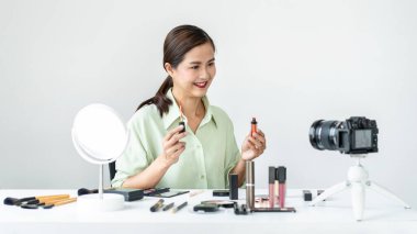 Kadın blogcu, makyaj malzemesi kozmetik inceleme ürünü ve canlı yayın videosunu ofis stüdyosundaki kamera ekranında öğretmenliğe sunuyor..