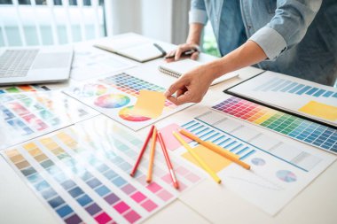 İş yerindeki grafik tabletinde renk seçimi ve çizim üzerine çalışan genç yaratıcı grafik tasarımcısı, yeni bir koleksiyon oluşturmak için ilhamda seçim renklendirmesi için renk örnekleri çizelgesi.