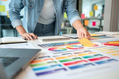 İş yerindeki grafik tabletinde renk seçimi ve çizim üzerine çalışan genç yaratıcı grafik tasarımcısı, yeni bir koleksiyon oluşturmak için ilhamda seçim renklendirmesi için renk örnekleri çizelgesi.