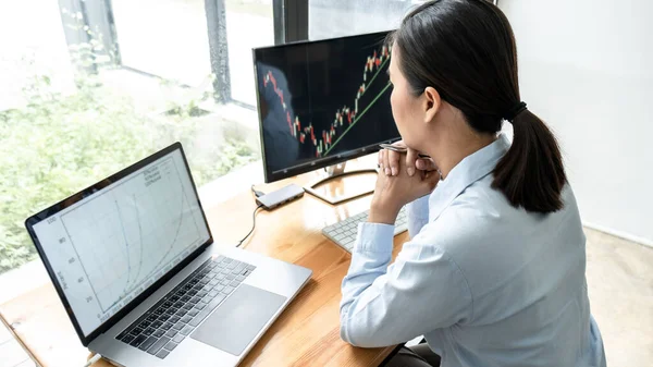 株式取引所に提示されたデータを表示画面でグラフデータを計画し 分析しているビジネスウーマンの投資家 — ストック写真