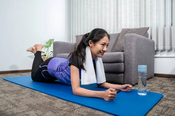 スポーツウェアの女性は 自宅で屋内リビングルームでヨガの練習を行うためにマットに座っている リラックスして健康的なコンセプト — ストック写真