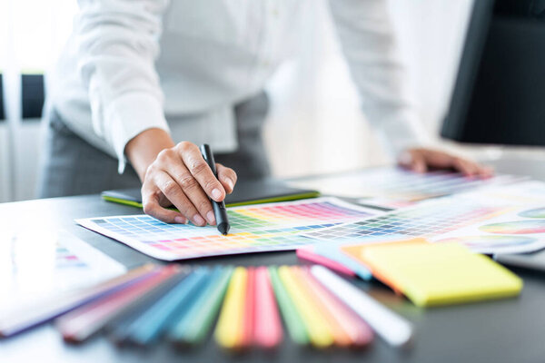 Young creative graphic designer working on color selection and drawing on graphics tablet at workplace, Color swatch samples chart for selection coloring in inspiration to create new collection