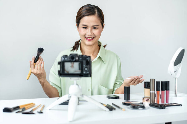 Женщина-блоггер показывает настоящее время макияж учебник красоты косметического обзора продукта и трансляции в прямом эфире потокового видео в социальной сети обучения онлайн на экране камеры.