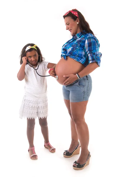 Ung flicka lyssna på hennes gravid mamma mage — Stockfoto