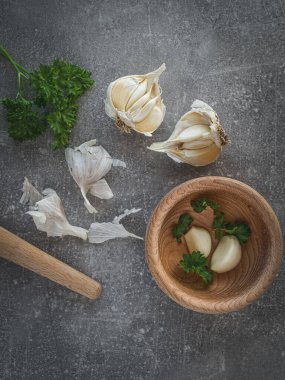 Sarımsak soğanları, taze maydanoz ve ahşap mutfak havanı..