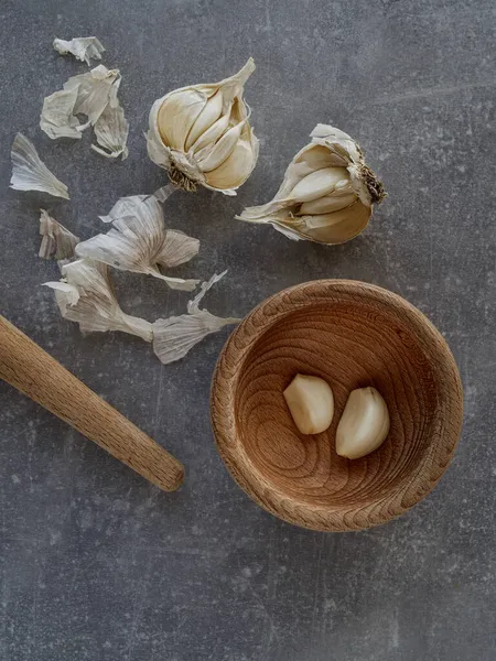 Cebulki czosnku i drewnianej zaprawy kuchennej na concete tle. Przestrzeń kopiowania — Zdjęcie stockowe