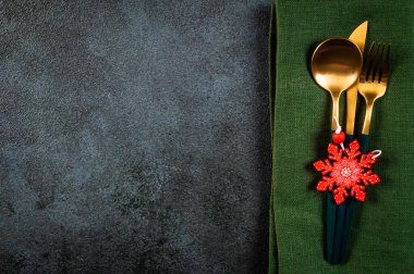 Karanlık arka planda modern bulaşık takımları ve süslemeleri olan bir Noel masası. Üst Manzara. Yeni yıl yeri ayarlama. Süslü Noel sofra takımı. Noel yeri ayarlama.