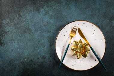 Karanlık arka planda modern bulaşık takımları ve süslemeleri olan bir Noel masası. Üst Manzara. Yeni yıl yeri ayarlama. Süslü Noel sofra takımı. Noel yeri ayarlama.