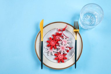 Mavi arka planda modern bulaşık takımı ve süslemeleri olan bir Noel masası. Üst Manzara. Yeni yıl yeri ayarlama. Noel sofra takımı. Noel yeri dekorasyonu. Dekorlu Noel yemeği takımı.