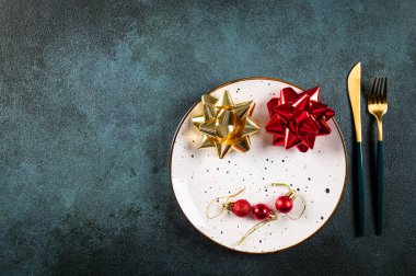 Karanlık arka planda modern bulaşık takımları ve süslemeleri olan bir Noel masası. Üst Manzara. Yeni yıl yeri ayarlama. Süslü Noel sofra takımı. Noel yeri ayarlama.