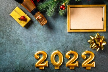 Noel fotoğraf çerçevesi koyu arkaplanda süsleme ile şablon oluşturur. Yukarıdan bak. Yeni yıl modeli. Şampanya şişesi ve dekorla yeni yıl kompozisyonu. Yeni yıl 2022