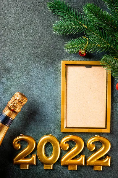 Noel fotoğraf çerçevesi koyu arkaplanda süsleme ile şablon oluşturur. Yukarıdan bak. Yeni yıl modeli. Şampanya şişesi ve dekorla yeni yıl kompozisyonu. Yeni yıl 2022