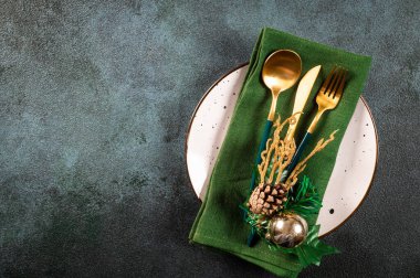 Karanlık arka planda modern bulaşık takımları ve süslemeleri olan bir Noel masası. Üst Manzara. Yeni yıl yeri ayarlama. Süslü Noel sofra takımı. Noel yeri ayarlama.