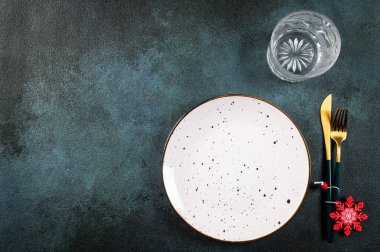 Karanlık arka planda modern bulaşık takımları ve süslemeleri olan bir Noel masası. Üst Manzara. Yeni yıl yeri ayarlama. Süslü Noel sofra takımı. Noel yeri ayarlama.