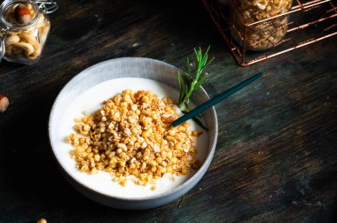 Sehpanın üzerinde fındık ve tahıllı lezzetli yoğurt servis ediliyor. Yulaf ezmeli granola. Cevizli tahıl gevreği. Sağlıklı kahvaltı. Vejetaryen granola