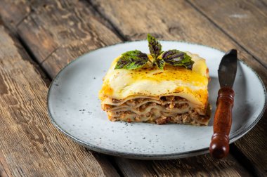 Ahşap arka planda lezzetli bir lazanya. Geleneksel İtalyan lazanyası. İtalyan yemeği. Lazanyayı kapat. Bolonez sosu. Sos haline geldi. Hala yiyecek dolu bir hayat. Ev yapımı et lazanyası.
