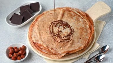Çikolatalı ve fındıklı krep. Kreplerin üzerine çikolata dökmek. Kreplere çikolata döküyorum. Maslenitsa blini. Shrovetide tatili. Shrove Salısı. Krep günü.