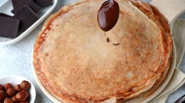 Çikolatalı ve fındıklı krep. Kreplerin üzerine çikolata dökmek. Kreplere çikolata döküyorum. Maslenitsa blini. Shrovetide tatili. Shrove Salısı. Krep günü.