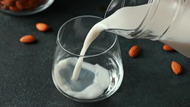 Derramando leite de amêndoa em vidro. Leite Vegan. Substituto de leite à base de plantas e sem lactose. Leite alternativo. Despejar leite em vidro. — Vídeo de Stock