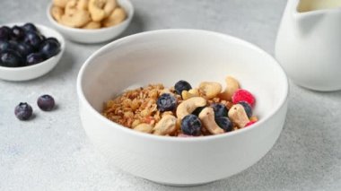 Beyaz arka planda tahıl gevreğine süt dökmek. Ceviz ve böğürtlenli granola. Sağlıklı kahvaltı. Tahıl yapıyorum. Sağlıklı yemek..