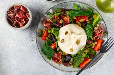 Burrata, krema ve inek sütünden yapılmış İtalyan taze peyniri. Domatesli ve salatalı Burrata salatası. Sağlıklı beslenme konsepti. Keto diyet salatası.