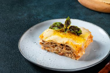 Koyu arkaplanda lezzetli bir lazanya. Geleneksel İtalyan lazanyası. İtalyan yemeği. Lazanyayı kapat. Bolonez sosu. Sos haline geldi. Hala yiyecek dolu bir hayat. Ev yapımı et lazanyası.